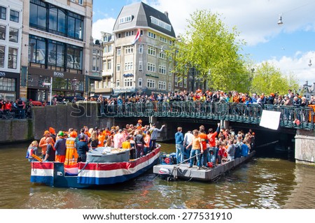 AMSTERDAM, NETHERLANDS-APRIL 27: People on Party Boat with crowd of people on the bridge on King\'s Day on April 27,2015. King\'s Day is the largest open-air festivity in Amsterdam.