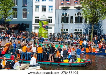 AMSTERDAM-APRIL 27: Party Boat on Singel canal with crowd of people on the street during King\'s Day on April 27,2015. King\'s Day is the largest open-air festivity in Amsterdam.