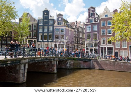 AMSTERDAM-APRIL 27:  King\'s Day boating through Amsterdam canals, people have fun on the bridge on April 27, 2015. King\'s Day (Koningsdag) is held on 27 April (the king\'s birthday) every year.