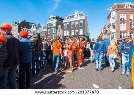 AMSTERDAM-APRIL 27: Locals and tourists celebrate King\'s Day on the bridge on Singel canal on April 27,2015, the Netherlands. King\'s Day is the largest open-air festivity in Amsterdam.