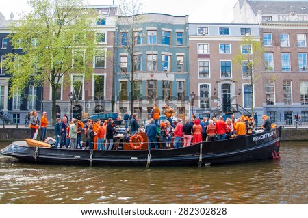 AMSTERDAM-APRIL 27: Locals and tourists have dance party on a boat King\'s Day along the Singel canal on April 27,2015, the Netherlands. King\'s Day is the largest open-air festivity in Amsterdam.