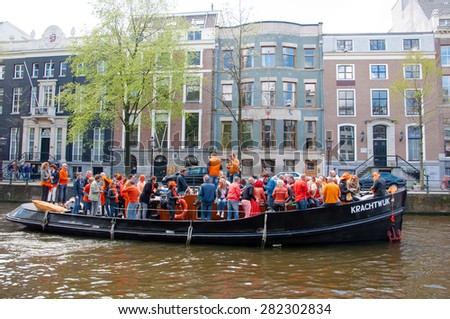 AMSTERDAM-APRIL 27: Locals have dance party on a boat King\'s Day along the Singel canal on April 27,2015, the Netherlands. King\'s Day is the largest open-air festivity in Amsterdam.