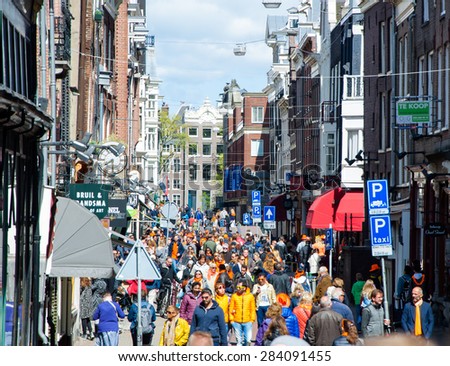 AMSTERDAM-APRIL 27: People on Amsterdam busy street celebrate King\'s Day on April 27,2015, the Netherlands. Kings Day is the biggest festival celebrating the birth of Dutch royalty.