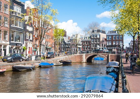 AMSTERDAM-APRIL 30: Amsterdam cityscape with row of cars, bikes and boats parked along the Amsterdam canal during the sunny day on April 30,2015, the Netherlands.