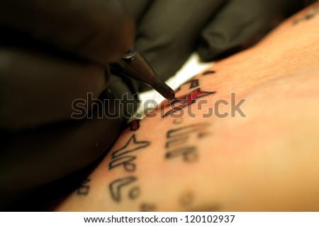 The close-up of a tattooing needle during the tattoo/Tattoo
