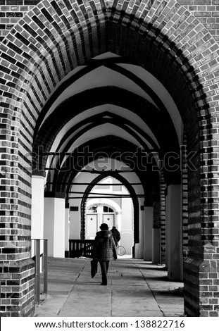 STRALSUND, GERMANY - APRIL 02: A woman goes along a round arch passage of the Saint Nikolai Church on April 02, 2013 in Stralsund. The church is part of the famous Old town Stralsund / Round arch