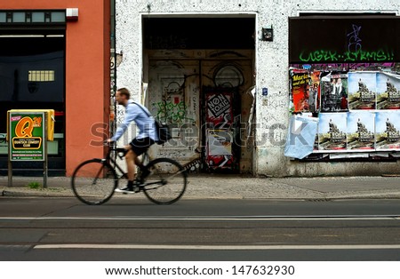 BERLIN GERMANY JULY 7 A cyclist passes an entrance with graffiti and posters in a shopping street on July 07 2012 in Berlin Berlin is the capitol of Germany Air non toxic BERLIN GERMANY JULY 7 A cyclist passes an entrance with graffiti and posters in a shopping street on July 07 2012 in Berlin Berlin is the capitol of Germany Air non toxic