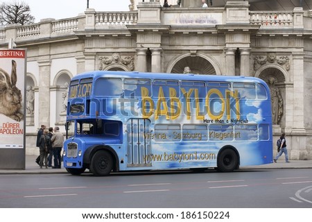 VIENNA, AUSTRIA - MARCH 31: A group of tourists standing next to a double-decker bus with distinctive advertising on March 30, 2014 in Vienna / Double-decker