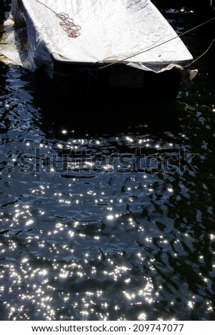 The photograph of a leashed rowing boat, which lies in the sparkling water / Rowing boat in the sparkling water