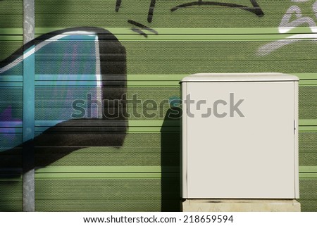 The photograph of an electrical box in front of a painted wall with little holes / Electric distribution box