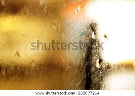 Abstract lights and lighting circuits behind a window covered with raindrops / Lights behind the rainy window