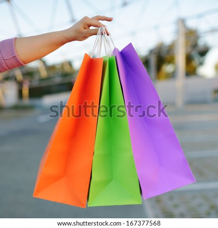 woman hand holding colorful paper shopping bags