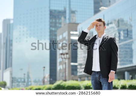young businessman looking to future opportunities, on background modern office buildings