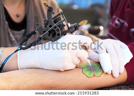 tattooer showing process of making a tattoo. Tattoo design in the form of four-leaf clover