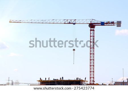 silhouette of construction workers and red crane on construction site at sunrise