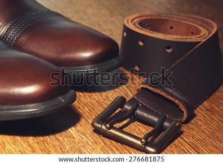 classic brown shoes and belt on wooden table. vintage picture