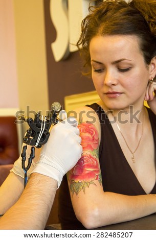 tattooer showing process of making a tattoo. Tattoo design in the form of rose