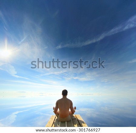 Rear View of a man Meditating in a Lotus Yoga Position at the lake with sun counter light