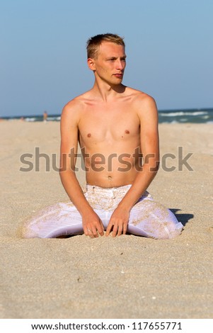 A young man in white pants on the sandy beach at the beach