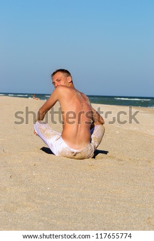 A young man in white pants on the sandy beach at the beach