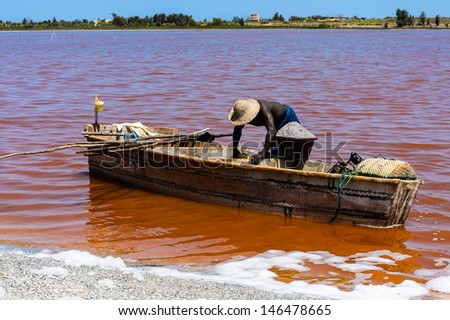 African man on the wooden boat over the Senegal red lake, called Lake Retba or Lac Rose