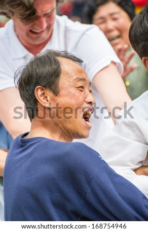 NORTH KOREA - MAY 1, 2012: Korean man actively participates in the tug of war game during the celebration of the International Worker\'s Day in N.Korea, May 1, 2012. May 1 is a holiday in 80 countries