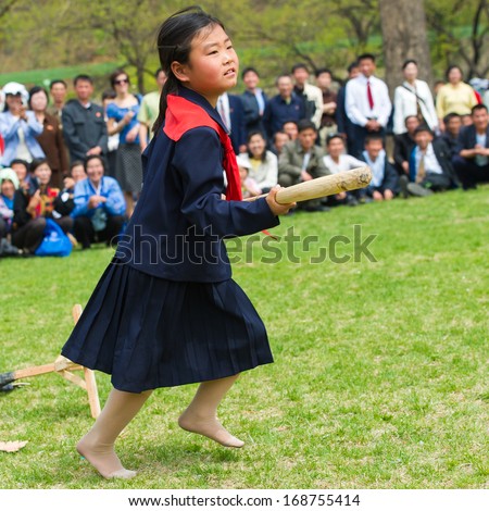 NORTH KOREA - MAY 1, 2012: Pioneer Korean girl with a bate plays the game due to the celebration of the International Worker's Day in N.Korea, May 1, 2012. May 1 is a national holiday in 80 countries