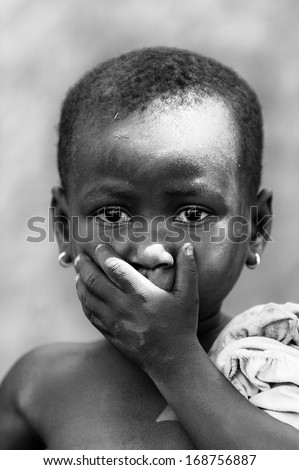 BENIN, MARCH 8, 2012: Unidentified Beninese girl shuts her mouth with a hand for the camera in Benin, Mar 8, 2012. People of Benin suffer of poverty due to the unstable economical situation
