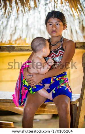 EMBERA VILLAGE, PANAMA, JANUARY 9, 2012: Unidentified native Indian girl holds her little sister in Panama, Jan 9, 2012. Indian reservation is the way to conserve native culture, languange, traditions