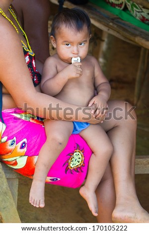 EMBERA VILLAGE, PANAMA, JANUARY 9, 2012: Unidentified native Indian woman holds her baby in Panama, Jan 9, 2012. Indian reservation is the way to conserve native culture