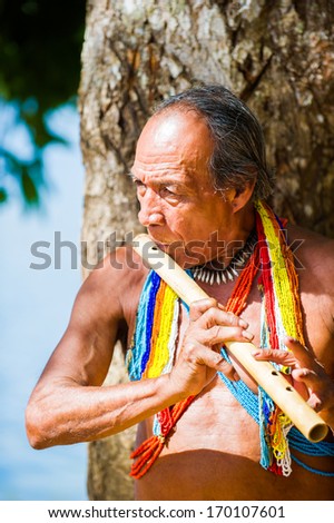 EMBERA VILLAGE, PANAMA, JANUARY 9, 2012: Unidentified native Indian man plays a flute in Panama, Jan 9, 2012. Indian reservation is the way to conserve native culture, languange, traditions