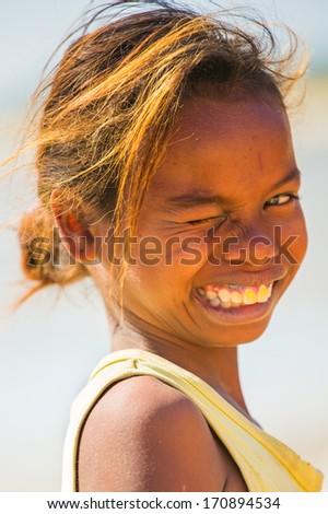 MADAGASCAR - JULY 5, 2011: Portrait of an unidentified cute funny smiling girl in a yellow shirt in Madagascar, July 5, 2011. Children of Madagascar suffer of poverty due to the unstable situation.