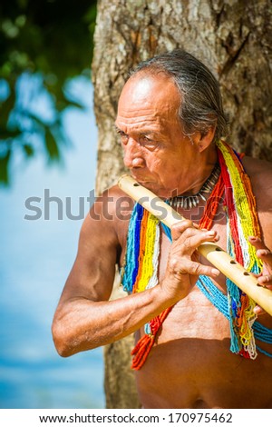EMBERA VILLAGE, PANAMA, JANUARY 9, 2012: Unidentified native Indian man plays a flute in Panama, Jan 9, 2012. Indian reservation is the way to conserve native culture, languange, traditions
