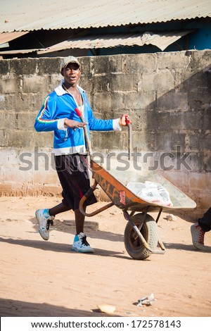 BANJUL, GAMBIA - MAR 14, 2013: Unidentified Gambian little man carries the carriage in Gambia, Mar 14, 2013. Major ethnic group in Gambia is the Mandinka - 42%