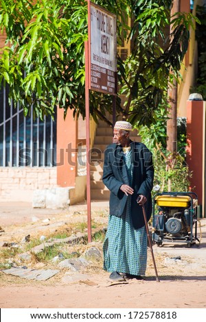 BANJUL, GAMBIA - MAR 14, 2013: Unidentified Gambian old man in long rope and a suit jacket walks with a baston in the street in Gambia, Mar 14, 2013. Major ethnic group in Gambia is the Mandinka - 42%