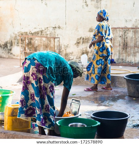 BANJUL, GAMBIA - MAR 14, 2013: Unidentified Gambian women wash the clothes in the street in Gambia, Mar 14, 2013. Major ethnic group in Gambia is the Mandinka - 42%