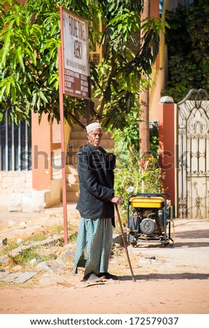 BANJUL, GAMBIA - MAR 14, 2013: Unidentified Gambian old man in long rope and a suit jacket walks with a baston in the street in Gambia, Mar 14, 2013. Major ethnic group in Gambia is the Mandinka - 42%