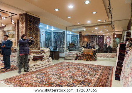 ISFAHAN, IRAN - JAN 7, 2014: Unidentified woman makes picture of a persian carpet on the wall of a shop in Iran, Jan 7, 2014. Persian carpet is an important part of Persian art and culture.