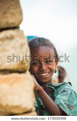 AKSUM, ETHIOPIA - SEP 24, 2011:Unidentified Ethiopian cute little girl in green dress near the stone wall in Ethiopia, Sep.24, 2011.Children in Ethiopia suffer of poverty due to the unstable situation