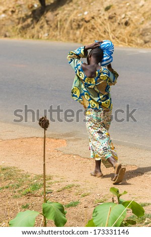 KARA, TOGO - MARCH 7, 2012: Unidentified Togolese woman carries the bag on the head in Togo, Mar 7, 2012. People in Togo suffer of poverty due to unstable economical situation
