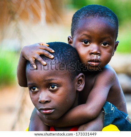 ANEHO, TOGO - MARCH 6, 2012: Unidentified Togolese little baby boy sit on his brother back and hugs him in Togo, Mar 6, 2012. Children in Togo suffer of poverty due to unstable economical situation