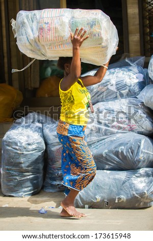 KARA, TOGO - MARCH 11, 2012: Unidentified Togolese girl carries really heavy bag over the head in Togo, Mar 11, 2012. People in Togo suffer of poverty due to unstable economical situation