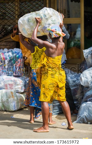KARA, TOGO - MARCH 11, 2012: Unidentified Togolese girl carries really heavy bag over the head in Togo, Mar 11, 2012. People in Togo suffer of poverty due to unstable economical situation