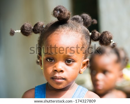 LIBREVILLE, GABON - MAR 6, 2013: Unidentified Gabonese little girl with a funny haircut smiles in Gabon, Mar 6, 2013. People of Gabon suffer of poverty due to the unstable economical situation