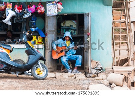 Antananarivo, Madagascar - June 29, 2011: Unidentified Madagascar Shop Seller Plays Guitar. People In Madagascar Suffer Of Poverty Due To The Slow Development Of The Country