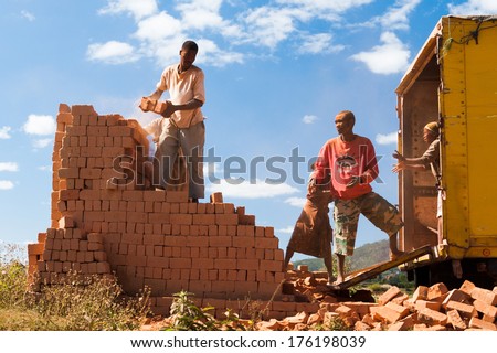 ANTANANARIVO, MADAGASCAR - JUNE 30, 2011: Unidentified Madagascar people move bricks into the track in the street. People in Madagascar suffer of poverty due to slow development of the country