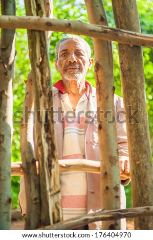 OMO, ETHIOPIA - SEPTEMBER 19, 2011: Unidentified Ethiopian old man stays behind the wooden fence. People in Ethiopia suffer of poverty due to the unstable situation