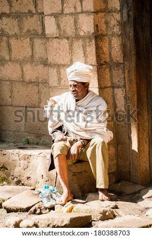 LALIBELA, ETHIOPIA - SEPTEMBER 28, 2011: Unidentified Ethiopian man sits at the porch of his house wearing old clothes. People in Ethiopia suffer of poverty due to the unstable situation
