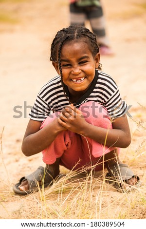 AKSUM, ETHIOPIA - SEPTEMBER 24, 2011: Unidentified Ethiopian beautiful smiling girl plays with hay. People in Ethiopia suffer of poverty due to the unstable situation