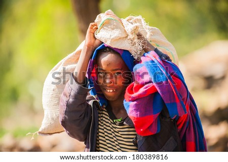 AKSUM, ETHIOPIA - SEPTEMBER 24, 2011: Unidentified Ethiopian girl carries a bag over her head. People in Ethiopia suffer of poverty due to the unstable situation
